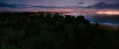 a view of the ocean at night from a hill