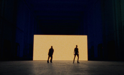 two people standing in front of a large screen