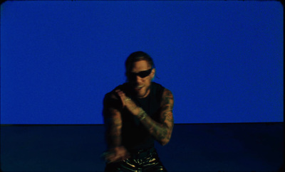 a man with tattoos and sunglasses sitting on a stool