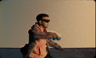 a man in a pink shirt and sunglasses holding a blue frisbee