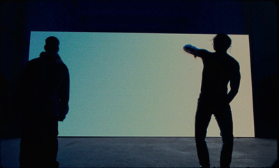 a man standing in front of a large screen holding a frisbee