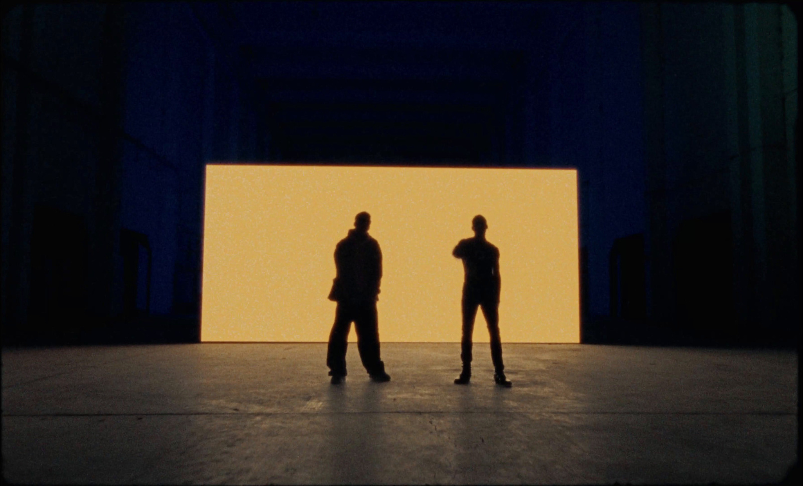 two people standing in front of a large screen