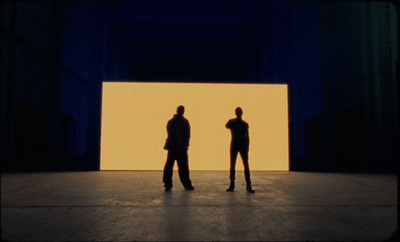 two people standing in front of a large screen