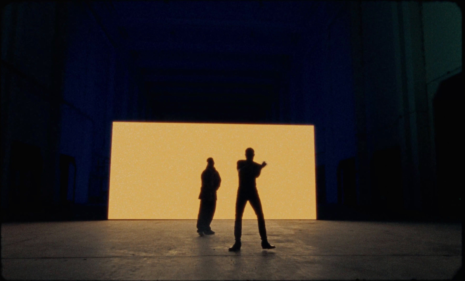 two people standing in front of a large screen