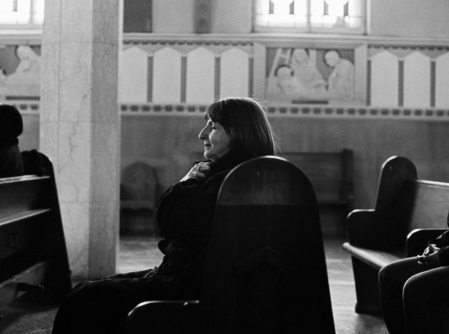 a black and white photo of a woman sitting in a church