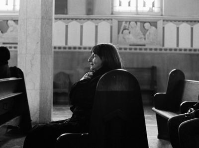 a black and white photo of a woman sitting in a church