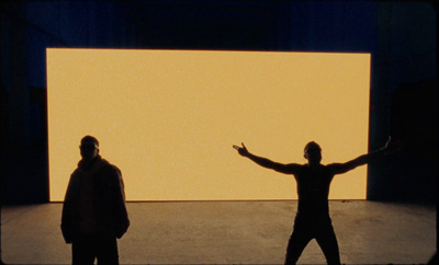 two men standing in front of a large screen