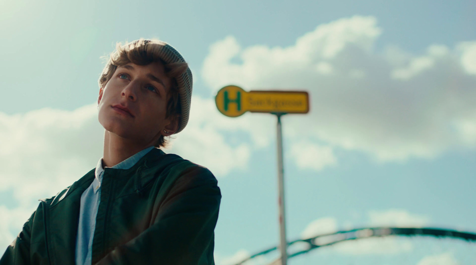 a young man standing in front of a street sign