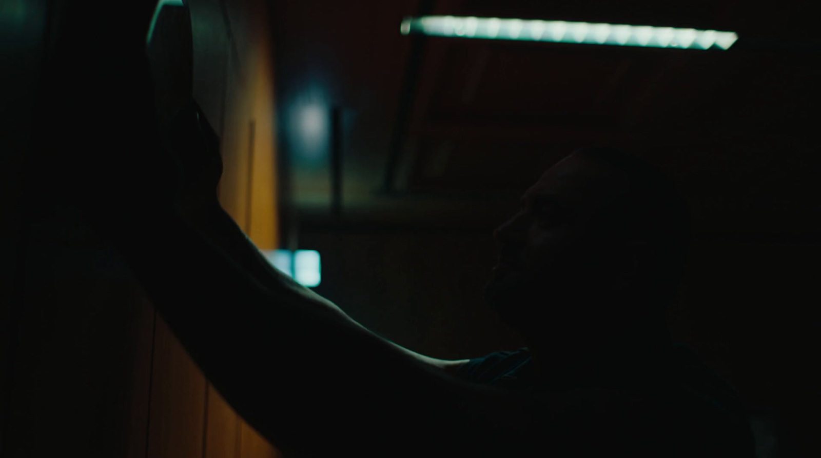 a man standing in a dark room holding a remote control