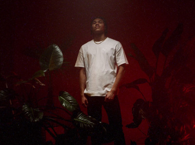 a young man standing in front of a plant