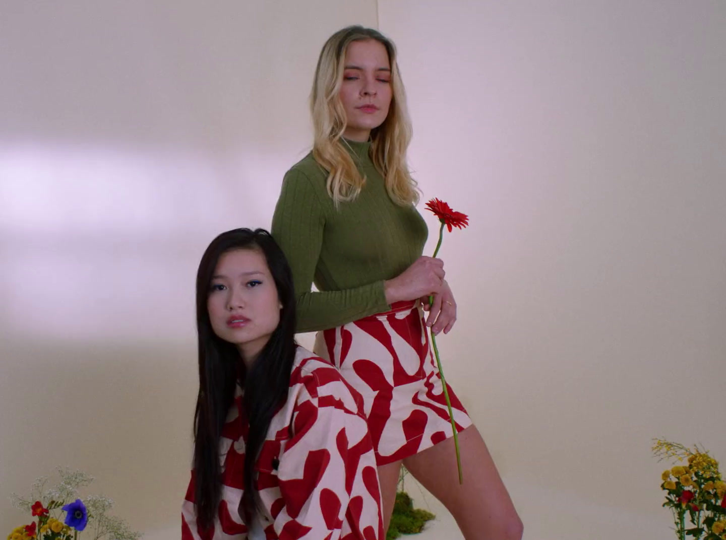 a woman standing next to a woman holding a flower