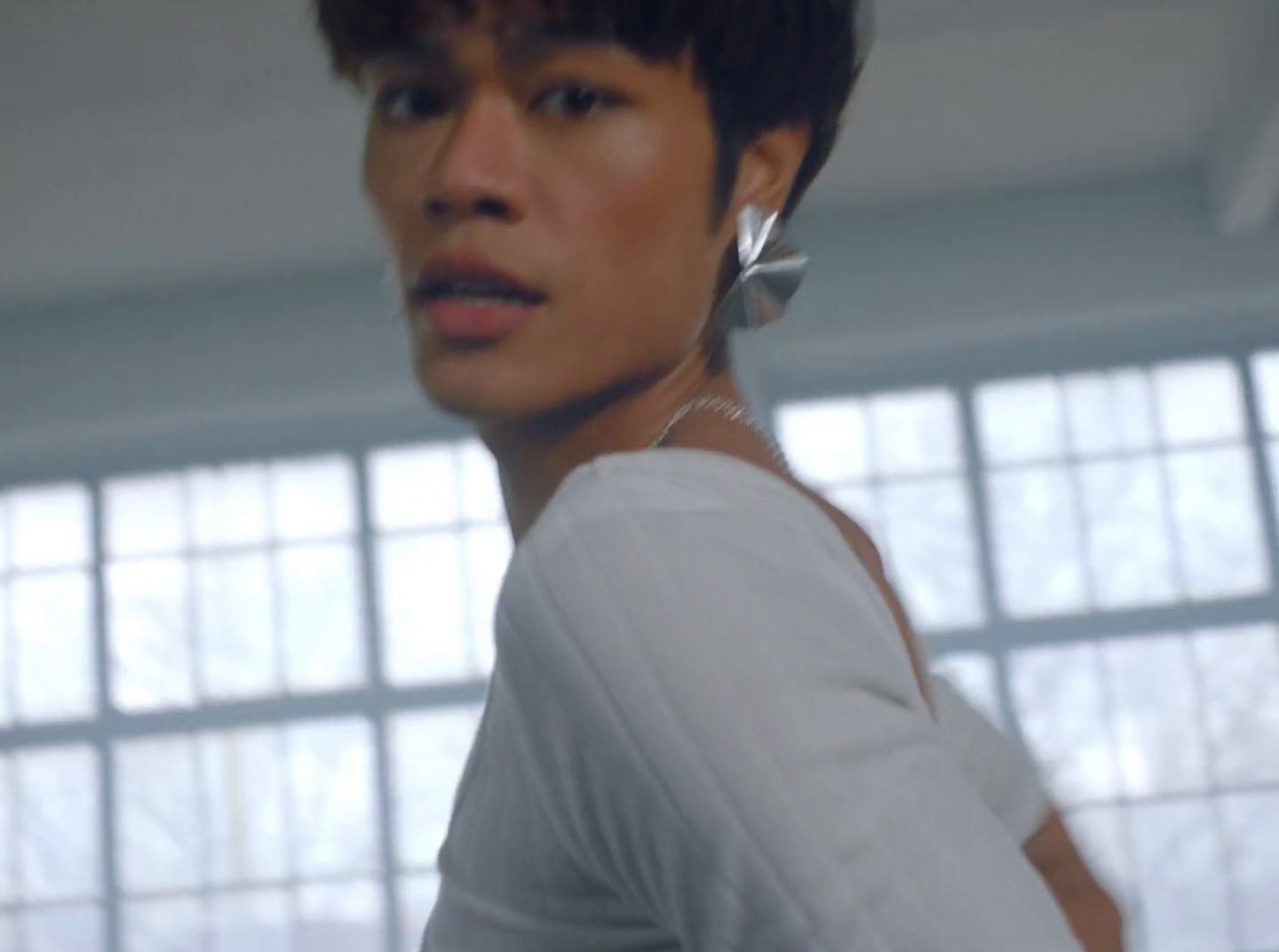 a woman in a white shirt with a pair of earrings on her ear