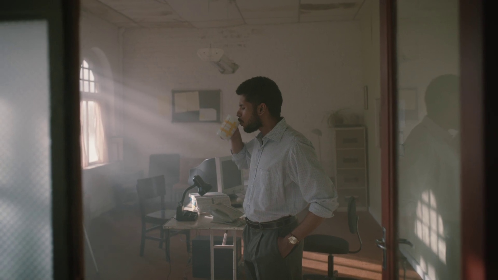 a man standing in a room drinking a beverage