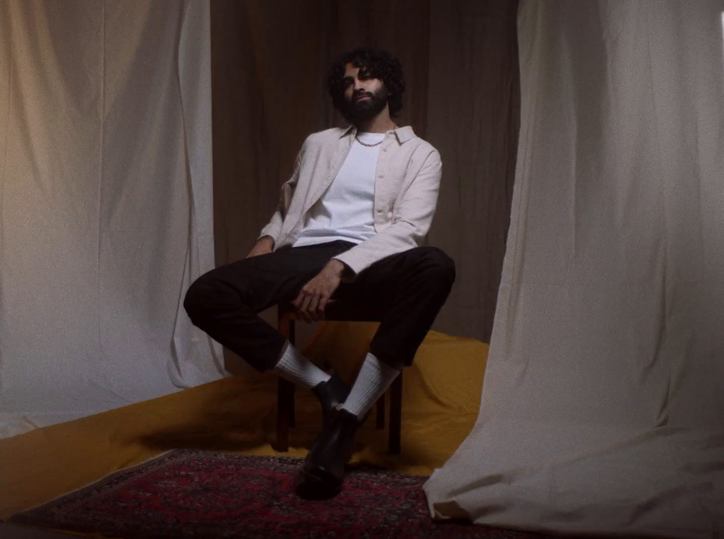 a man sitting on a chair in front of a curtain