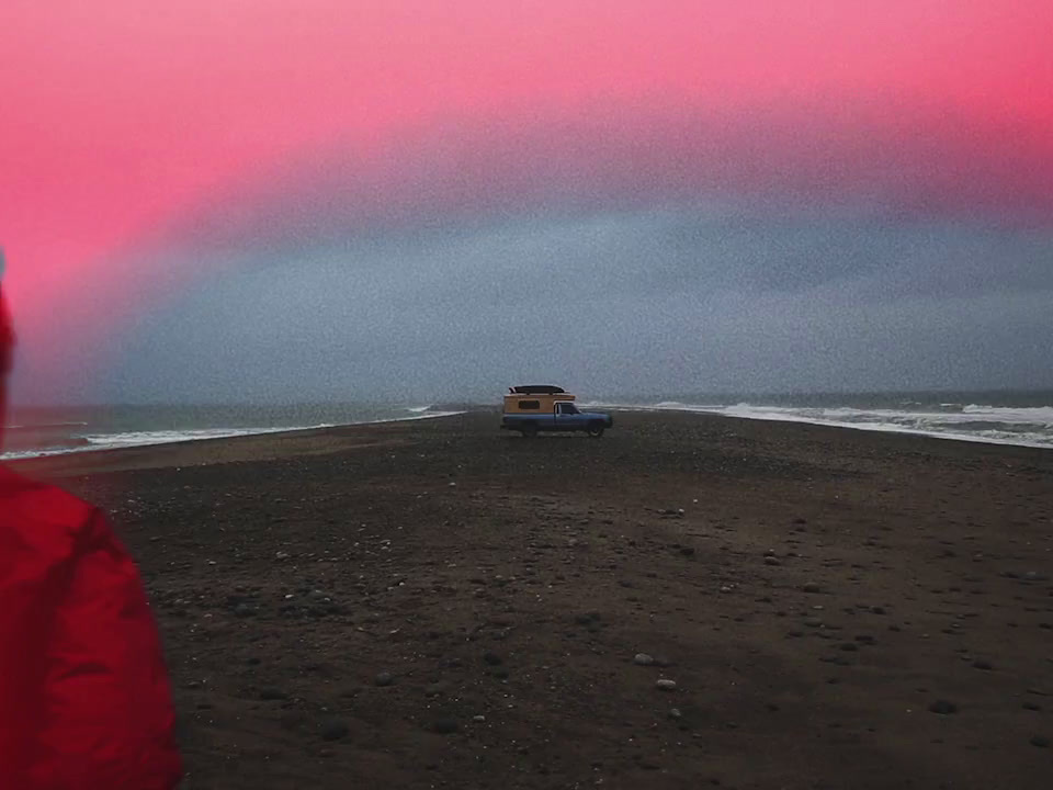 a person in a red jacket standing on a beach