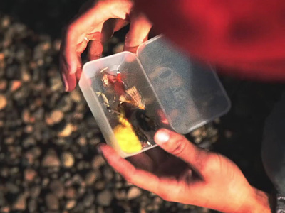 a person holding a plastic container with a small toy in it