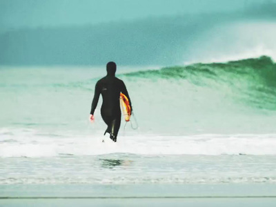 a man in a wet suit carrying a surfboard into the ocean