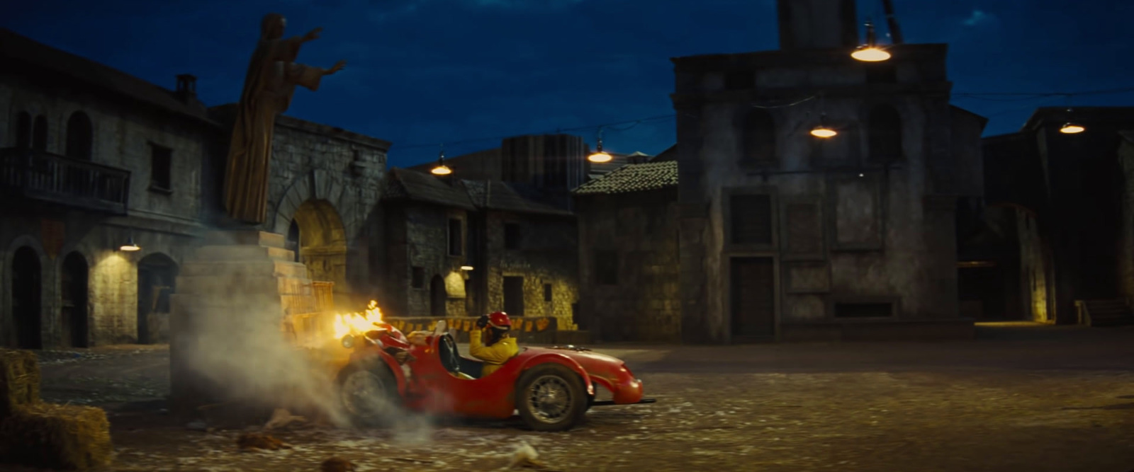 a red car driving down a street next to tall buildings