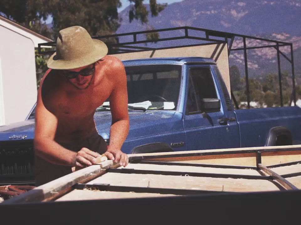 a shirtless man working on a wooden boat