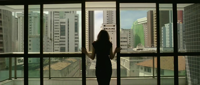 a woman standing in front of a window looking out at a city