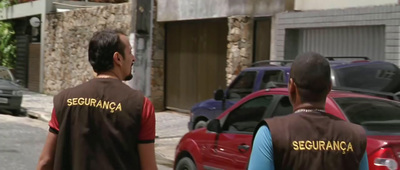 two men in brown vests walking down a street