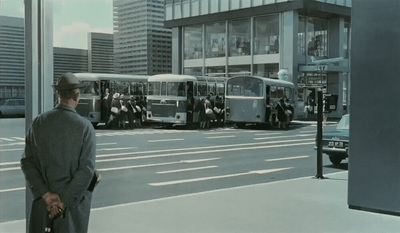 a man standing on the side of a street next to a bus