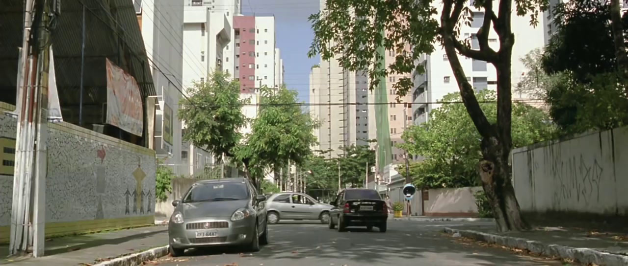 two cars driving down a street next to tall buildings