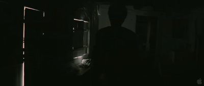 a man standing in a dark room next to an open door