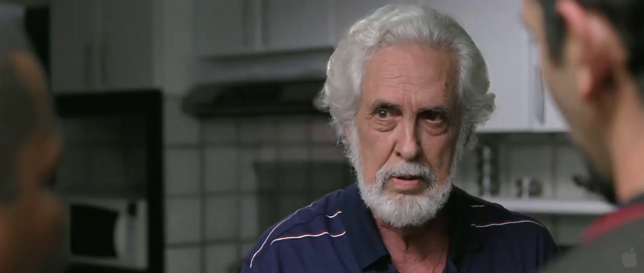 a man with white hair and a beard talking to another man