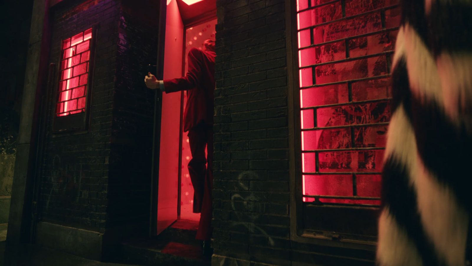 a man in a red suit standing outside of a building