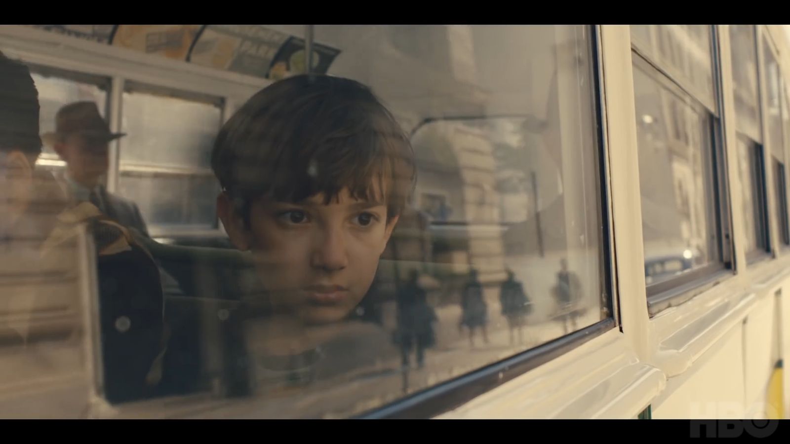 a boy looking out the window of a bus