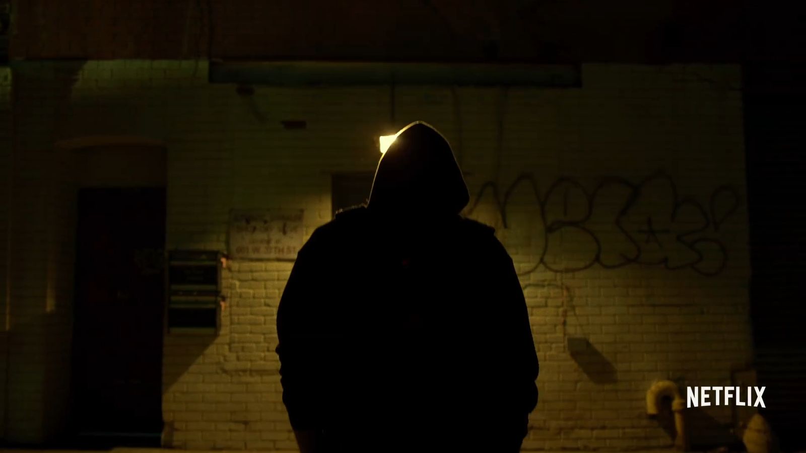 a person standing in a dark room with graffiti on the wall