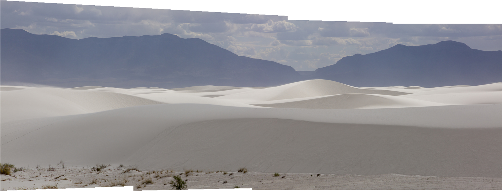 a large group of sand dunes with mountains in the background