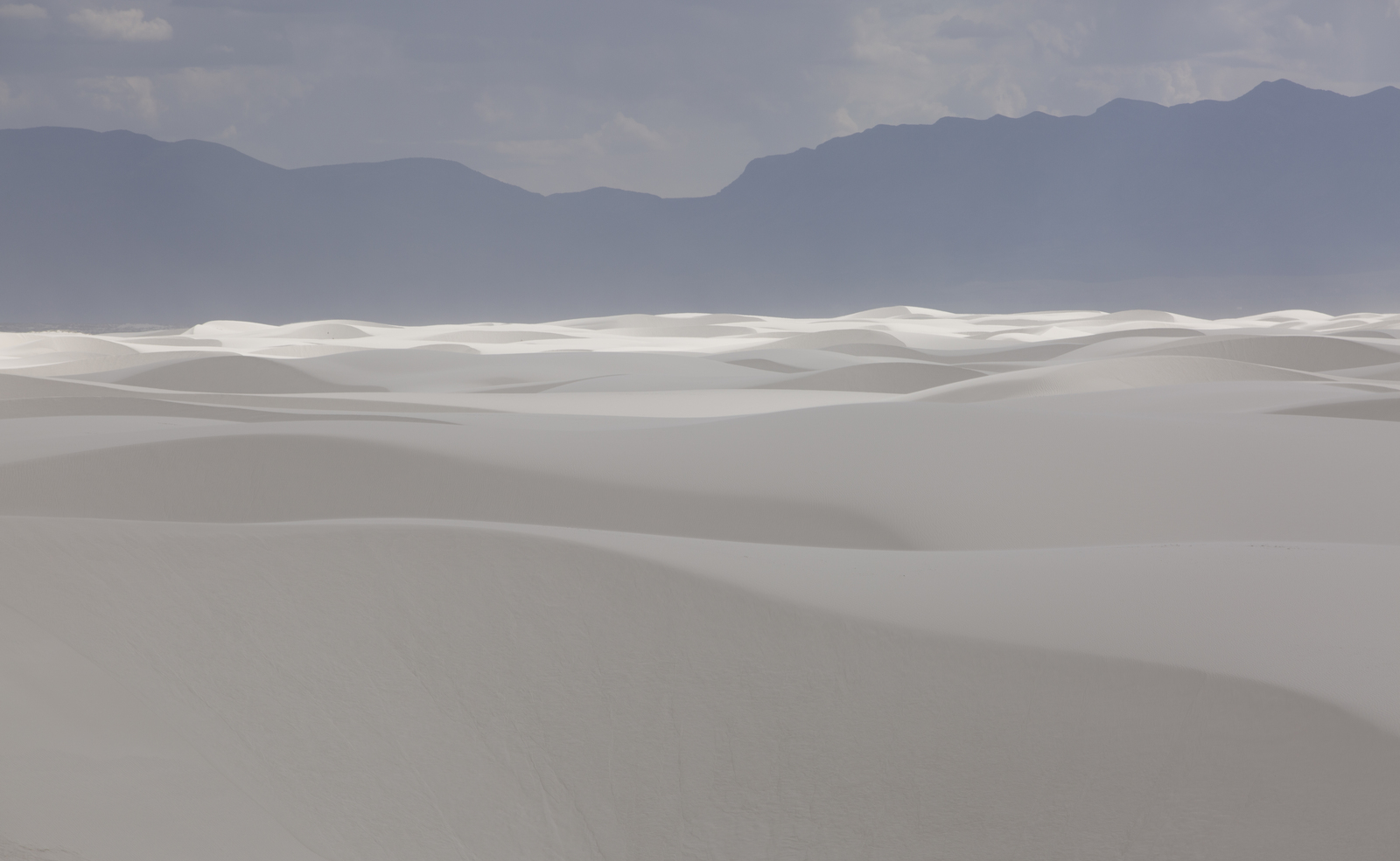 a large expanse of white sand with mountains in the background