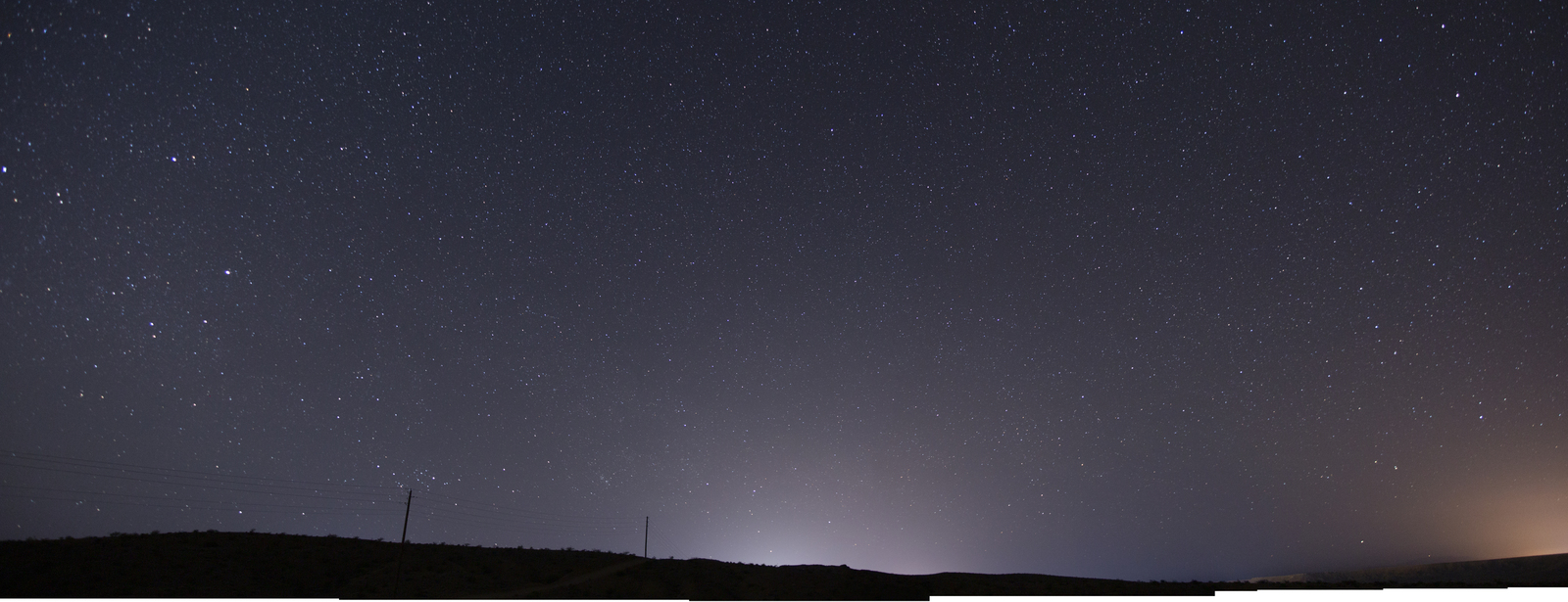 the night sky with stars above a hill