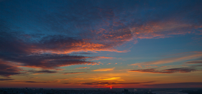 the sun is setting over a city with tall buildings