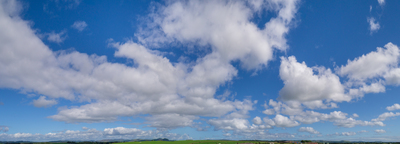 a green field with a few clouds in the sky