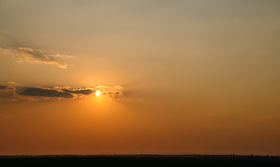 the sun is setting over the horizon of a field