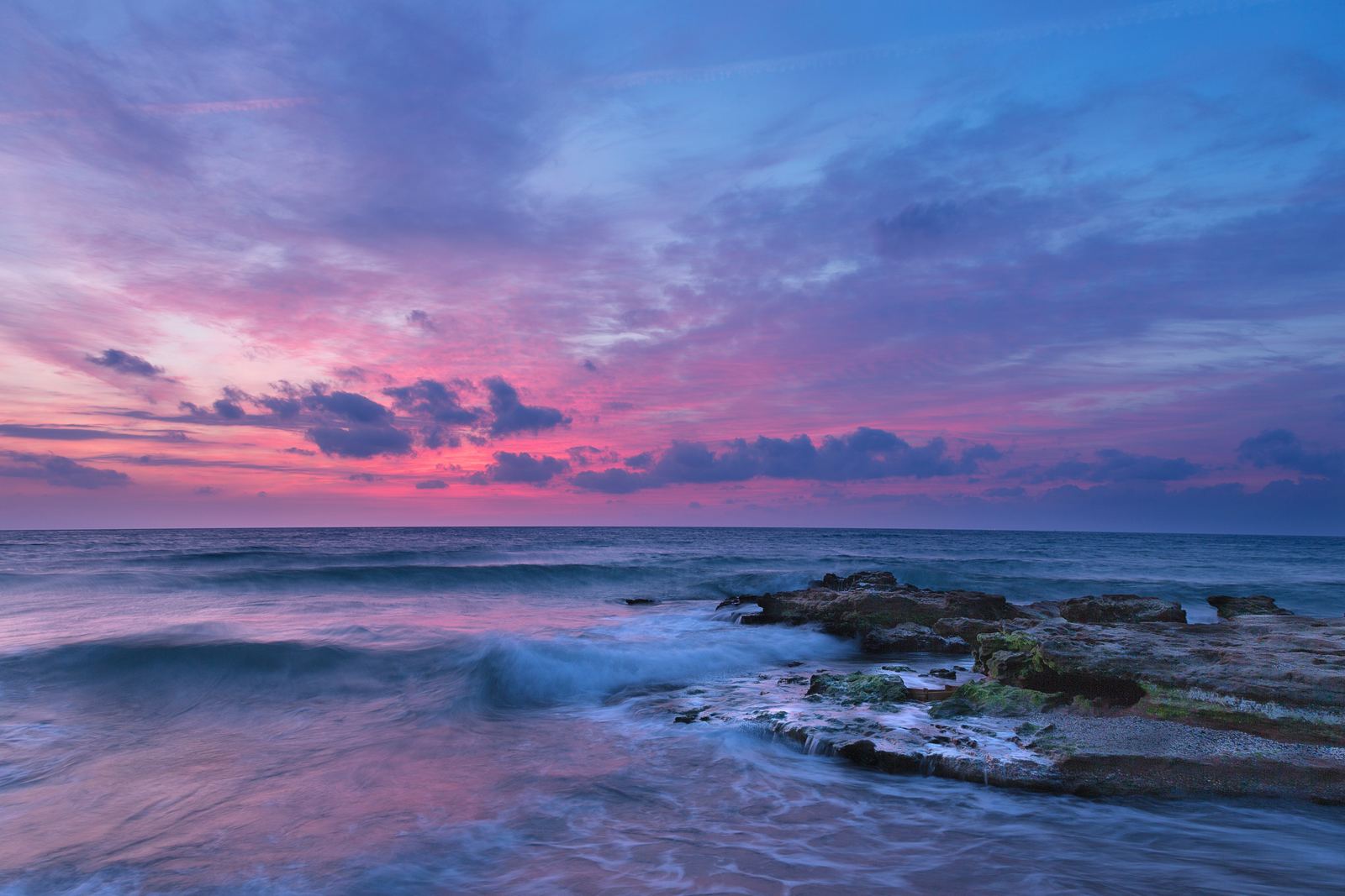 a beautiful sunset over the ocean with waves