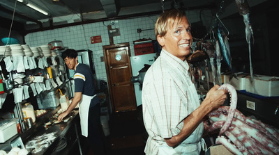 a man standing in a kitchen holding a piece of meat