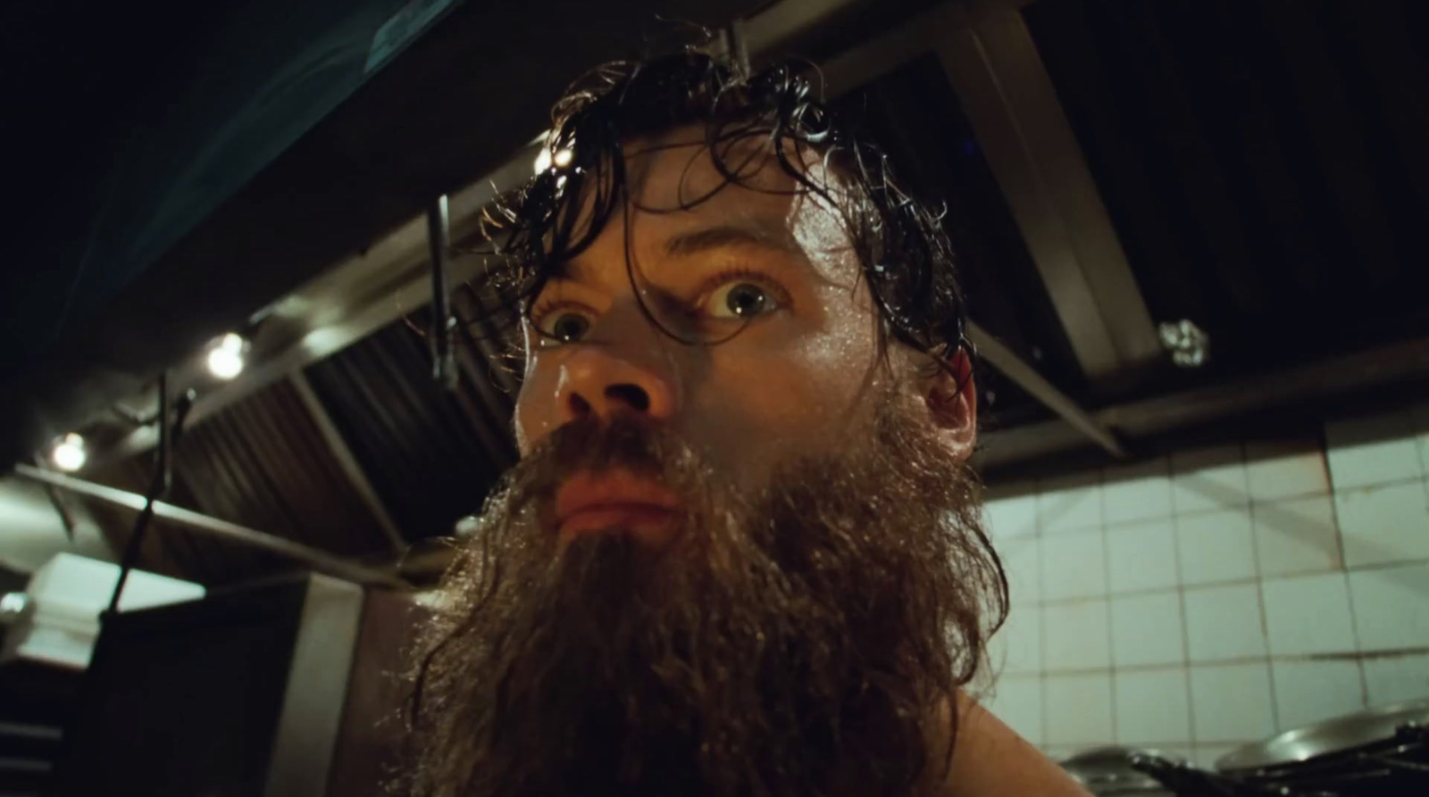 a man with a long beard standing in a kitchen