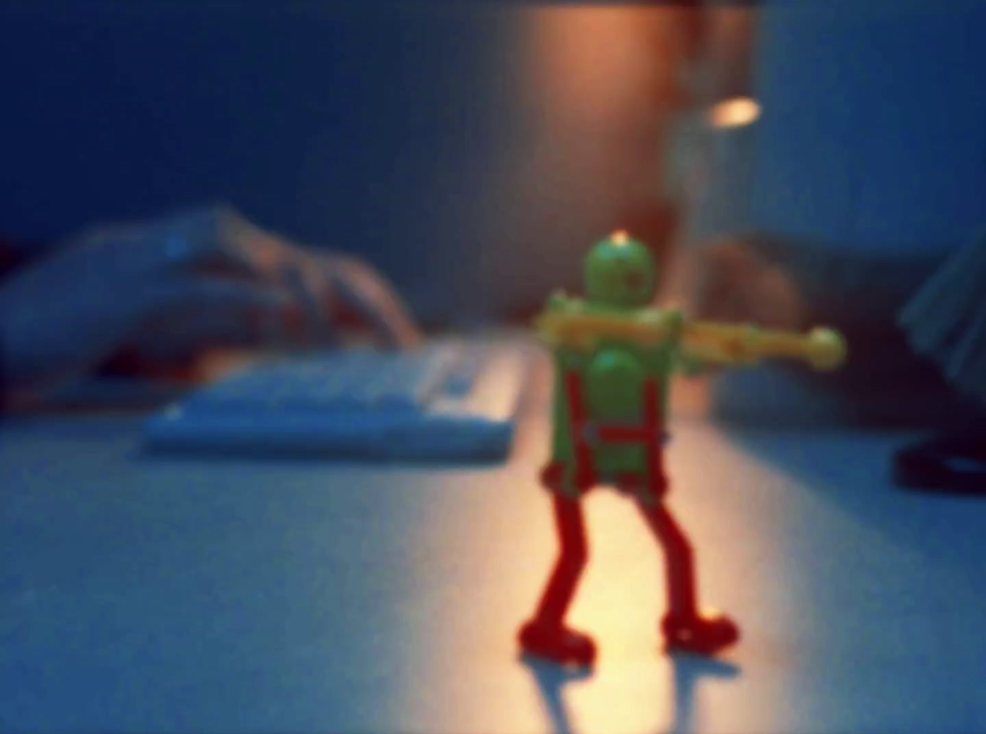 a toy figure standing on a desk in front of a computer