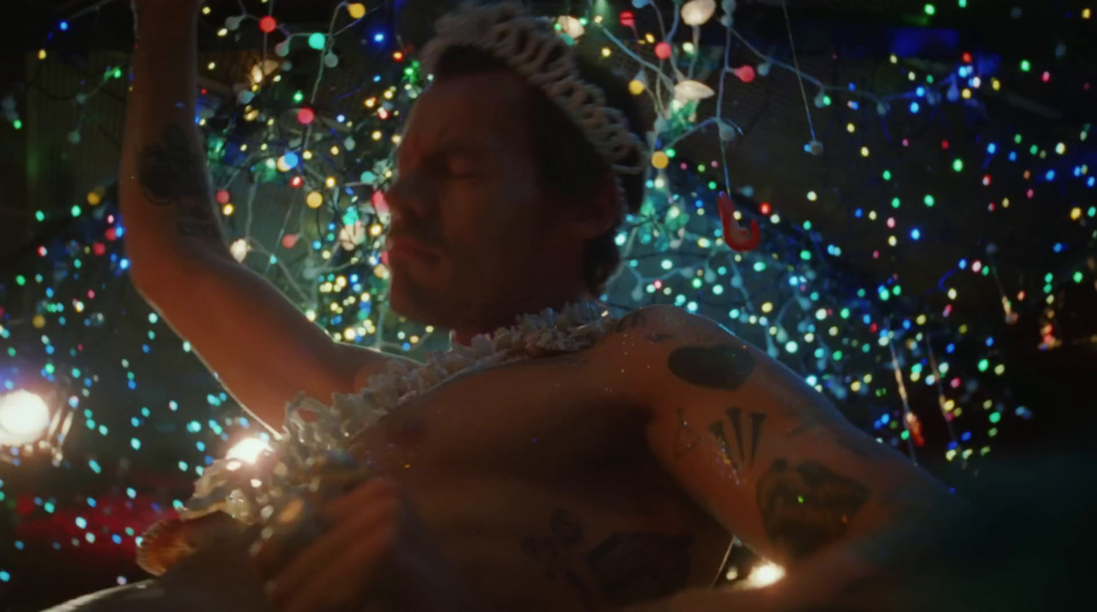 a man wearing a tiara standing in front of a christmas tree