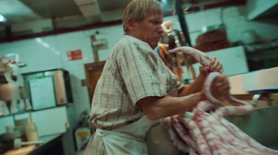 a man in a butchers shop holding a large piece of meat