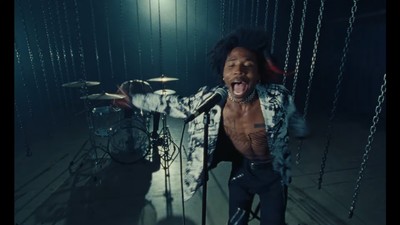 a man with a shirt on and a drum set in front of him