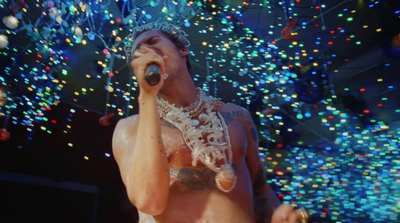 a shirtless man singing into a microphone