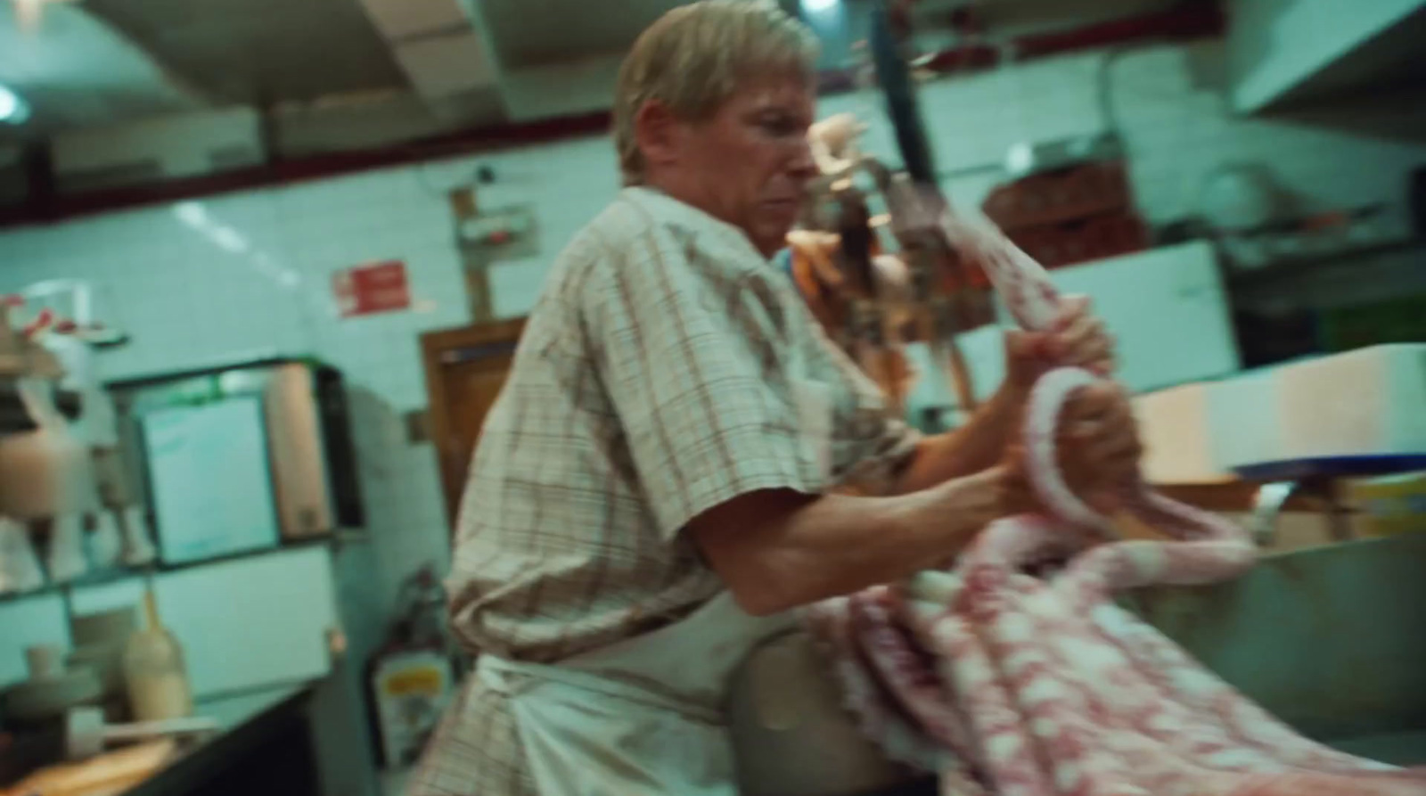 a man holding a large piece of meat in a kitchen