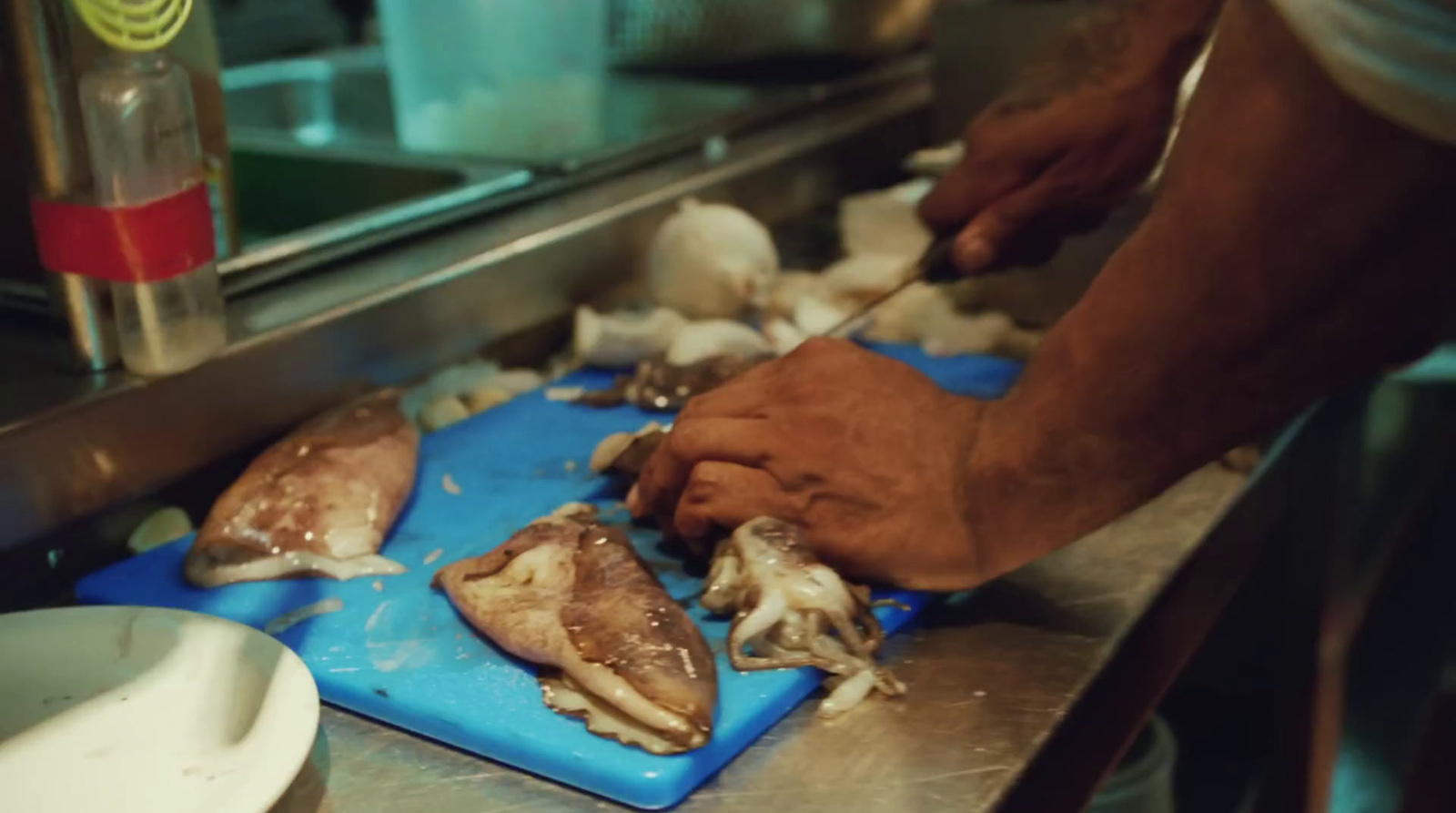 a person cutting mushrooms on a blue cutting board