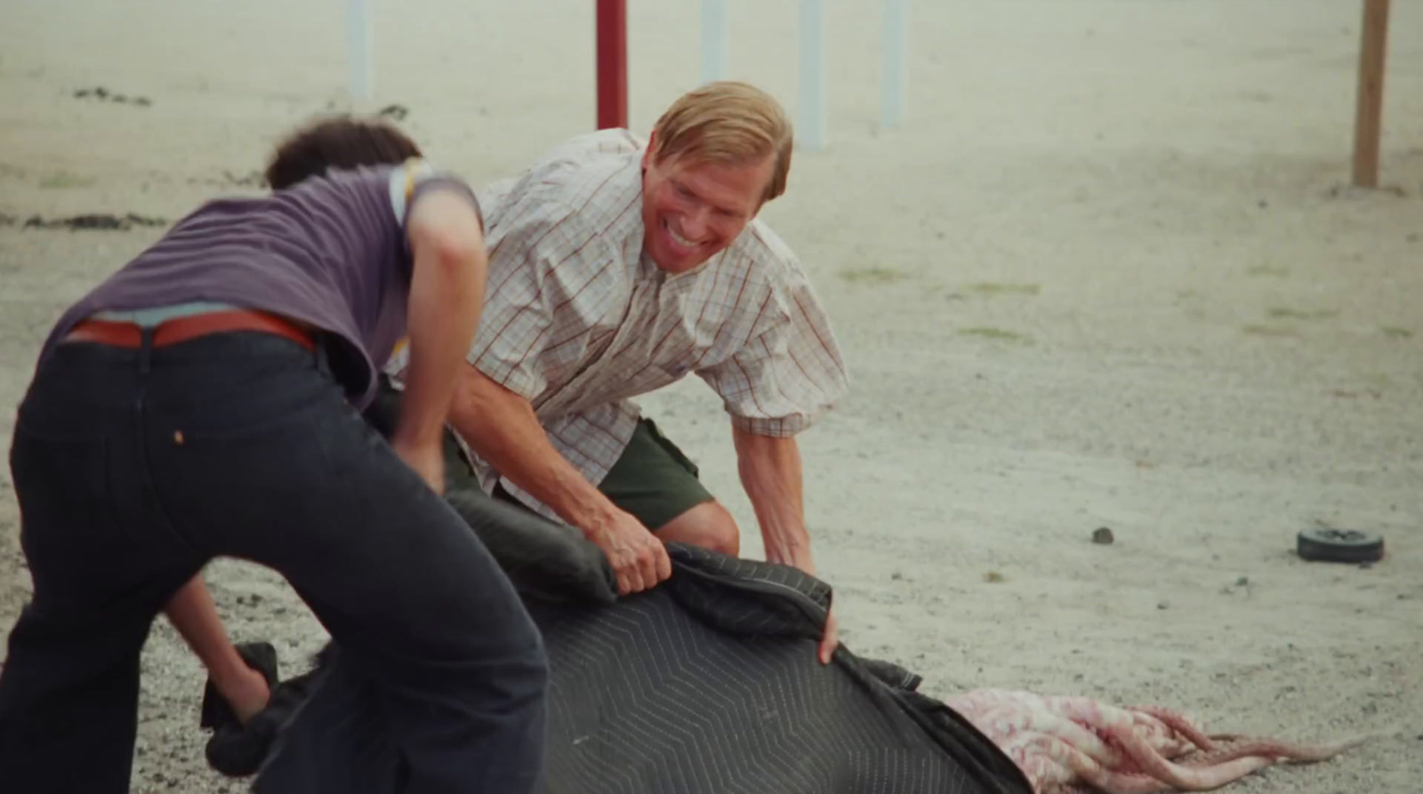 a couple of people standing over a dead animal