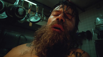 a man with long hair and a beard in a kitchen